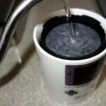 Hot water rinsing an AeroPress filter.