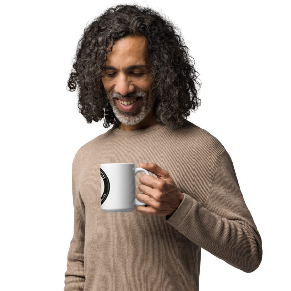 Man looking down at the white Gambit Coffee mug he is holding.